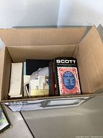 Top view of cardboard box showing stamp catalogues and envelopes inside.