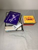 Top view of the collection showing multiple DVDs and books stacked, featuring the purple 'Concert for George' and yellow 'The Beatles Love' boxed set on top.