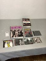 Photo showing entire lot on table including 2 books, 1 DVD and 6 CDs all related to The Rolling Stones