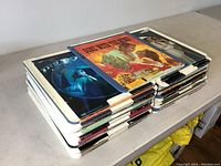Two stacks of video discs in large plastic cases with visible cover art of various movies and performances, stacked on a table.