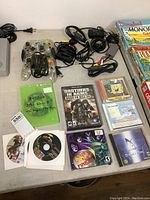 Full view of all items on table showing controllers, cables, PC game discs, Nintendo DS cartridges, and game box