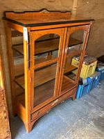 Front view of the vintage solid wood display cabinet showing glass doors and construction details.