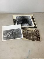 Photo of five vintage black and white photographs showing various subjects including a dark stone tunnel, aerial view of prison, and a train locomotive.
