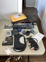 Photo of LG Blu-Ray player, Sharp VCR, various cables, power adapters, audio selector device and instruction manuals on table.