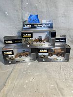 Photo showing all three boxed CASE Norscot diecast tractor toys including 580 Super M Series 2 Loader/Backhoe, 721D Wheel Loader, and Articulated Truck.