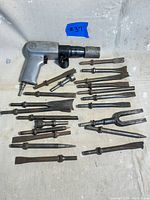 Air hammer with all chisel attachments laid out showing the full lot contents.