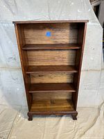 Front view of the antique oak bookshelf showing the three adjustable shelves and the overall structure.