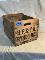 Front and side view of the antique wooden crate showing the advertising text 'H.F. & T.B. BYRD, INC. TIMBERVILLE, VA.' and cut-out handle on the side.