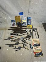 Photo showing various automotive hand tools and small parts together on a white sheet background.