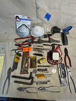 Full assortment of hand tools including Snap On Allen wrench set, knives, respiration masks, various pliers, and other tools arranged on a concrete floor.