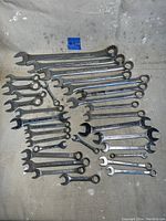 Photo showing an organized layout of 22 mechanics wrenches on a surface, displaying different sizes and types (combination wrenches) clearly for condition and count verification.