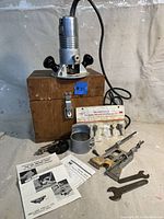 Millers Falls 6850 router mounted on wooden box next to router bits, fence accessories, wrench, Allen key, and manuals.