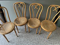 Four vintage bentwood chairs with curved backs and caned seats arrangement, showing overall appearance and style.