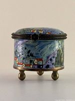 Front and side view of round copper enamel trinket box showing hand-painted Van Gogh 'Starry Night' inspired design, decorative metal trim, and three metal ball feet.