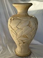 Front and side view of tall cream ceramic floor vase with high relief leaf and flower design.