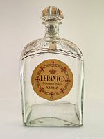 Front view of empty Lepanto Gonzalez Byass Xerez brandy bottle showing the circular label and gilded decorative designs near neck.