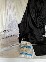 Wide view of all lot items including white drape, black blackout room divider, placemats, aquarium gravel, and black mesh organizer