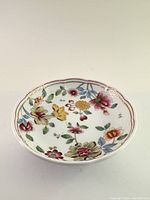 Front view of the hand-painted floral porcelain dish showing vibrant colors and scalloped edge with gold trim.