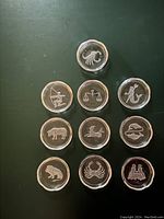 Ten Val St Lambert astrological zodiac crystal beverage coasters arranged in a triangular pattern on a dark surface, showing the scalloped edges and frosted etched zodiac sign designs.