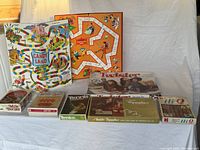 Full view of the lot showing game boards Candyland and Fantasyland at the back with boxed games Twister, HiQ, The Trippler, Kwazy Quilt, Tennis, Mille Bornes, and Rennis in front.