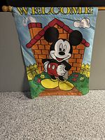 Full view of vintage fabric banner showing Mickey Mouse with colorful house and 'WELCOME' text.