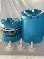 Two blue plastic water storage jugs side by side with three white valves placed in front