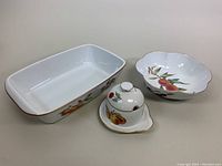 Overview photo of the three serving dishes: rectangular lasagne dish, covered sugar/honey bowl with attached under-plate, scalloped bowl, all with fruit motif and gold trim