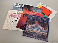 Six vinyl album covers stacked: Genesis, STYX, Meat Loaf, Trooper, Bowie, Sting, showing front artwork for each.