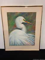 Full view of the framed pastel painting of a white bird with multicolored background.