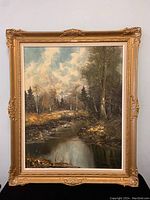 Full view of framed landscape print showing river and trees, ornate gold frame with damage