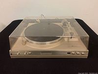 Turntable front with closed dust cover on black surface