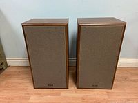 Front view of the pair of vintage Advent 5002 speakers side by side showing fabric grille and wood veneer.