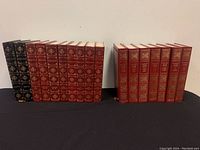 Two sets of hardcover books side by side on a shelf. The left set includes black and red volumes of Victor Hugo works, and the right set includes multiple red volumes of Maurice Druon's 'Les Rois Maudits' with gold embossing.