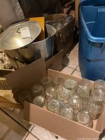 Box of assorted clear glass jars seen from above on tile floor