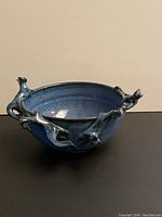 Front view of handmade pottery bowl showing blue glaze and cat accents on the rim