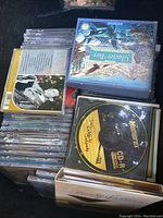 Stack of CDs in jewel cases and CD-Rs showing various music titles including classical and pop artists.