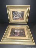 Two framed prints standing and laying down showing a white house with fence and garden pathway.