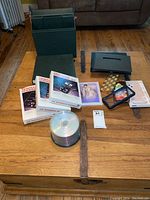 Full lot display with photo albums, stationery sets, blank CDs, phone covers, and an art book on a wooden chest.