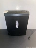 Front view of the black Staples paper shredder showing the transparent bin window and power cord.