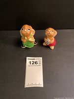Two Pendelfin ceramic rabbit figurines against black background with measurement card showing about 3-4 inches tall.