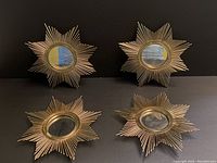 Four retro style metal starburst mirrors displayed on black background