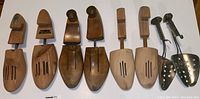 Nine wood shoe forms arranged in a row showing different styles and sizes including metal and wood components.