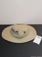 Front and top view of beige colored wide-brim Tilley hat showing stitching and ventilation eyelets