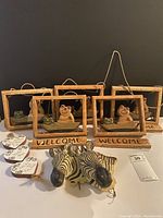 Full view of lot showing two zebra heads, wooden framed welcome signs with frog figurines, and heart-shaped plaques