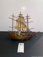 Front view of wooden boat lamp showing fabric sail, three masts with candle-style lamps, and electrical cord.