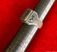 Close-up view of 925 silver men's ring with small blue stones on top, set on a ring sizer showing size 12.