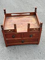 Front and top angled view of antique Chinese wooden jewelry box showing drawer fronts, carved posts, and wood grain detail.