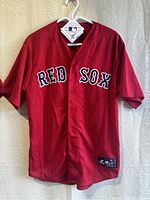 Front view of red Majestic Cool Base Boston Red Sox baseball jersey with button front and stitched 'RED SOX' text.