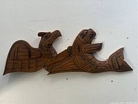 Full view of the wooden plaque showing the killer whale and thunderbird carved figures.