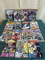 Photo showing all 15 Marvel Age comic books laid out in three rows on a cloth surface.
